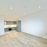 Modern kitchen in bright, spacious room with wood flooring.