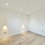 Minimalist white room with wood flooring and lighting