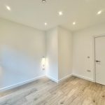 Minimalist room with wooden flooring, white walls.