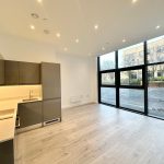 Modern kitchen with large windows and wooden flooring.
