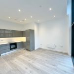 Modern kitchen with grey cabinets and wooden floor.