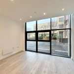 Empty room with large window and wood flooring.