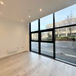 Empty room with large windows and wooden flooring.
