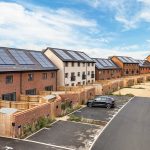 Modern houses with solar panels and parking spaces.