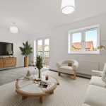 Modern living room with neutral decor and large windows.