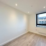 Empty room with wooden floor and large window.