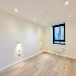 Minimalist room with wooden floor and large window.