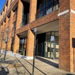 Modern brick building on a sunny street corner.
