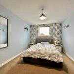 Modern bedroom with grey walls and floral wallpaper.