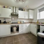 Modern kitchen with white cabinets and appliances.