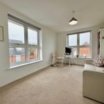Bright home office with sofa and large windows.