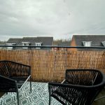 Balcony with chairs overlooking rooftops.