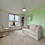 Bright home office, desk, chair, sofa, bookshelf.