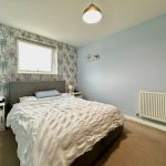 Cosy bedroom with floral wallpaper and modern decor.