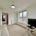 Bright home office with sofa and computer screen.