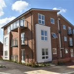 Modern brick apartment building with balconies and path.