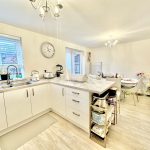 Modern white kitchen with island and dining area.