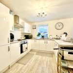 Modern white kitchen with clock and appliances.
