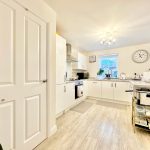 Modern kitchen with white cabinets and wooden floor.