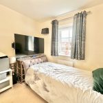 Cosy bedroom with TV and window view.