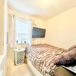 Small cosy bedroom with TV on wall.