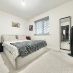 Modern bedroom with large bed and mirror.