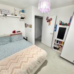 Cosy bedroom with bed, shelves, and bookcase.