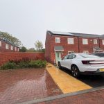 Modern terraced houses with parked cars in driveway.