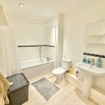 Modern white bathroom with bathtub and sink.