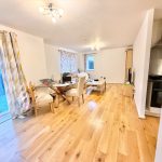 Spacious living room with wooden flooring and dining area.
