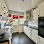 Modern kitchen with white cabinets and black countertops.