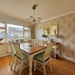 Dining room with wooden table and patterned wallpaper.