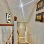 Carpeted stairway with framed art on walls