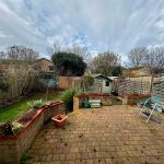 Patio with garden, shed and overcast sky.