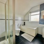 Modern bathroom with shower, bathtub, sink, and toilet.