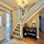 Bright hallway with staircase and wooden furniture.
