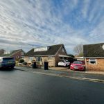 Suburban street with parked cars and houses.