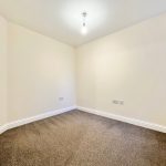 Empty room with beige walls and brown carpet.