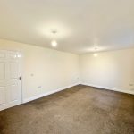 Empty beige room with carpet and two lights.