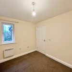 Empty small room with beige walls and window.