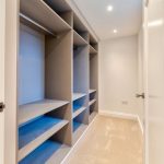 Empty walk-in wardrobe with shelves and hangers