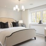 Elegant bedroom with beige decor and large window.