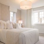 Modern bedroom with neutral decor and large window.