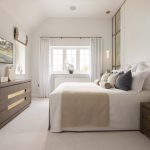 Modern bedroom with neutral decor and large window.