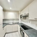 Modern kitchen with white cabinets and appliances.