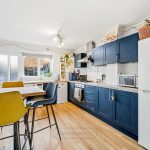 Modern kitchen with blue cabinets and dining area.