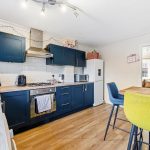 Modern kitchen with blue cabinets and bar seating.