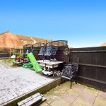 Garden with patio, slide, and chairs.