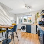Modern kitchen with dining area and blue cabinets.