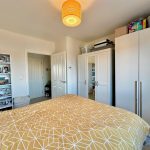 Modern bedroom with shelves and yellow bedspread.
